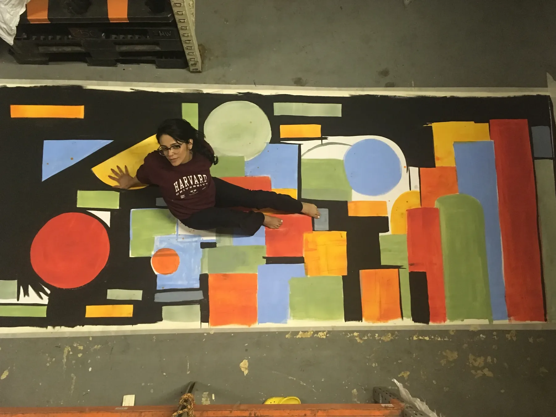 Nico Belico working across a large geometric floor painting
