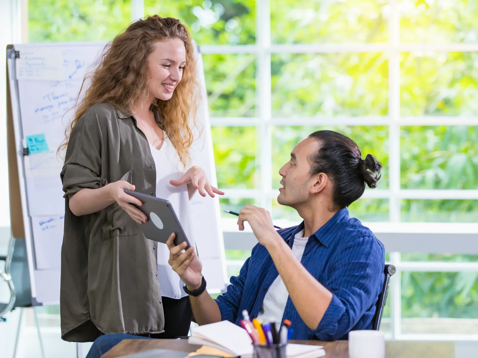 A designer showing a client the proposed mural design on a tablet
